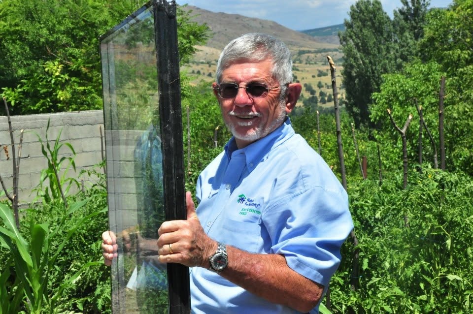 John Finnerty at a construction site holding a double-glazed window glass